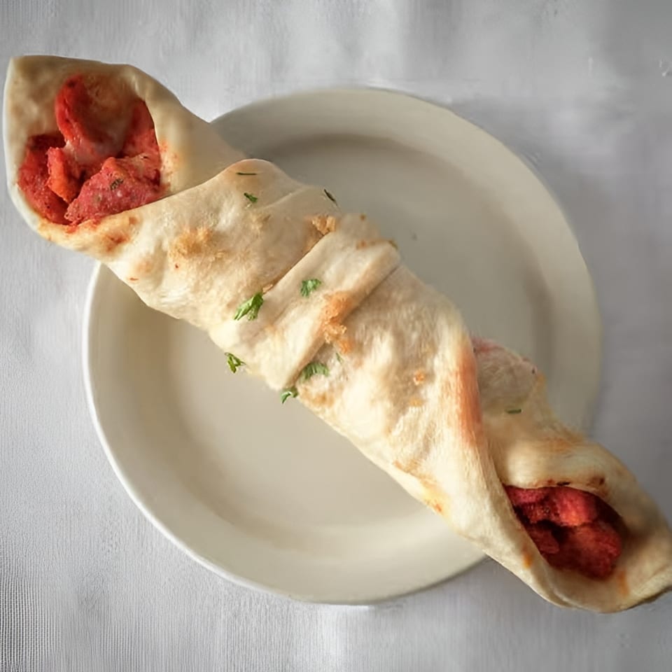 A chicken tikka roll, a popular Indian street food, on a white plate.
